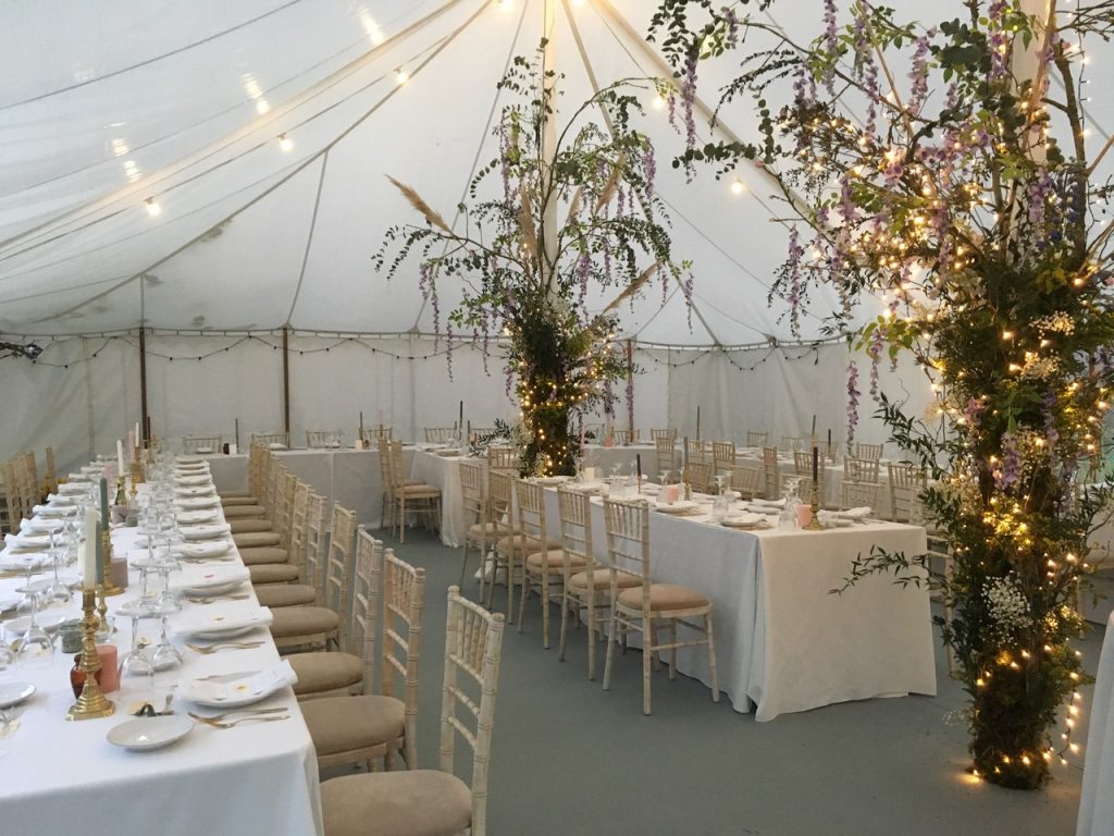 Traditional marquee built by Archers Marquees for a spring wedding in Somerset. It has elephant grey carpet, festoon lighting and trestle tables with limewash chiavari chairs