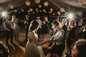 White paper lanterns at night, above a wooden parquet dancefloor in a lined sports hall. Installed by Archers Marquees at Prior Park College