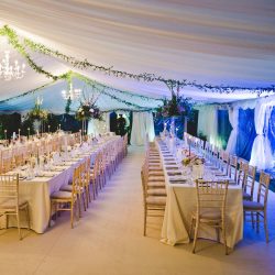 12m Clearspan marquee with ivory linings, hard flooring and beige carpet, with trestle tables and limewash chiavari chairs, built by Archers Marquees in Oxford